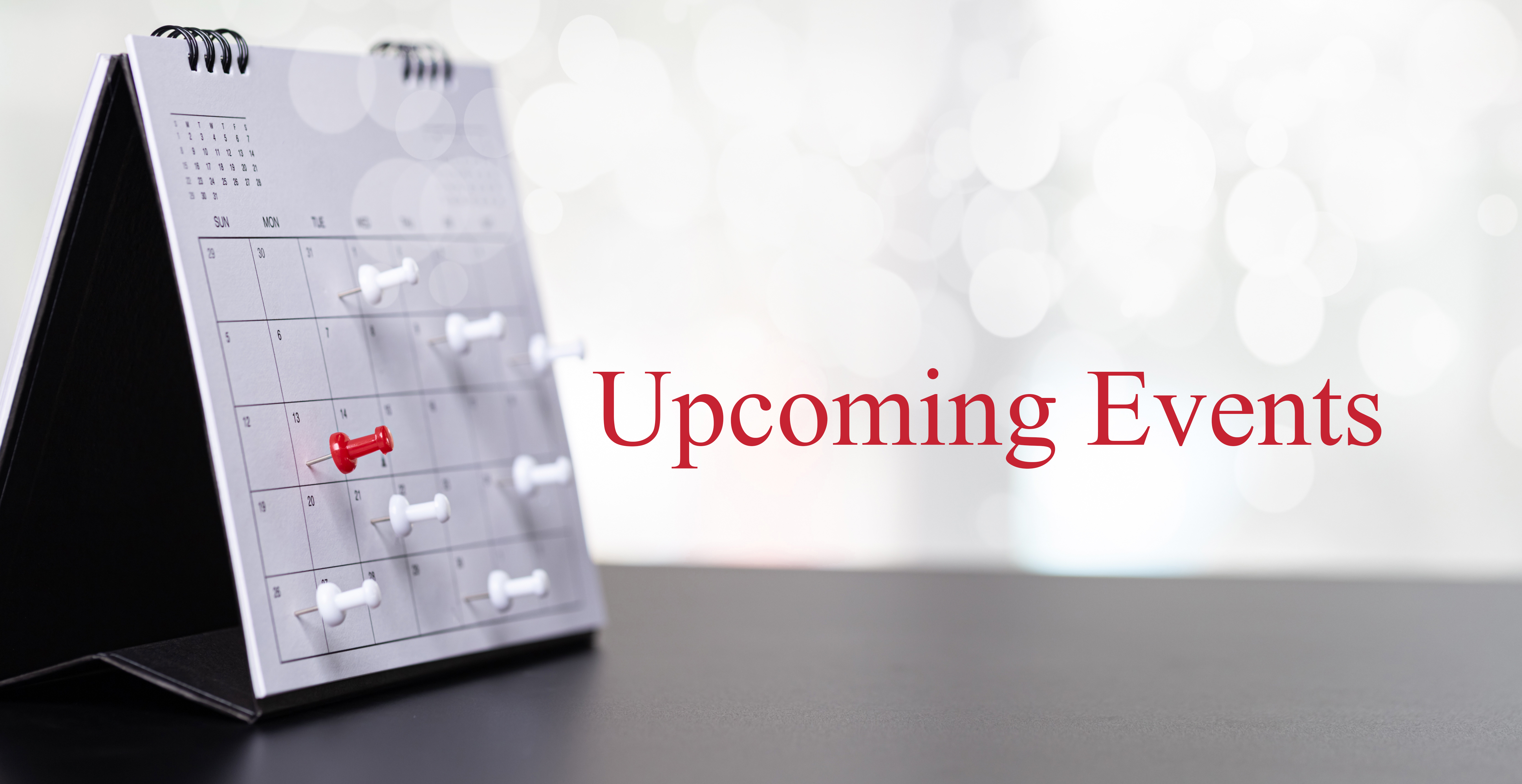 Desk Calendar opened to a month view with a date marked in red, set against a light background. The words "Upcoming Events" appear in red text beside the calendar