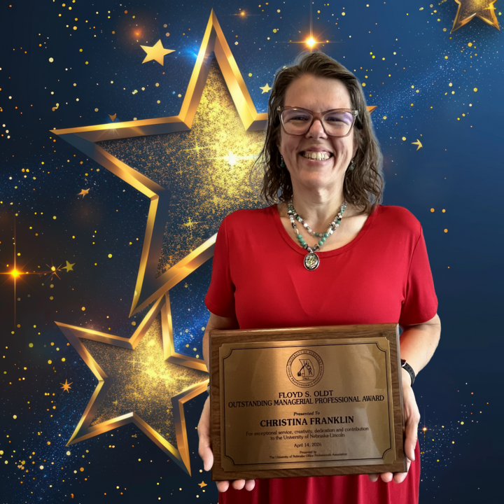Person with red dress, holding a plaque, in form of blue background with gold stars