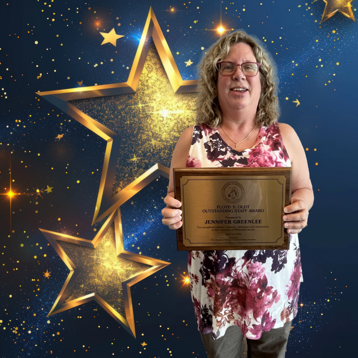 Award recipient holding plaque against a starry blue and gold background.